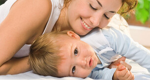 A mother playfully resting her head on her baby.