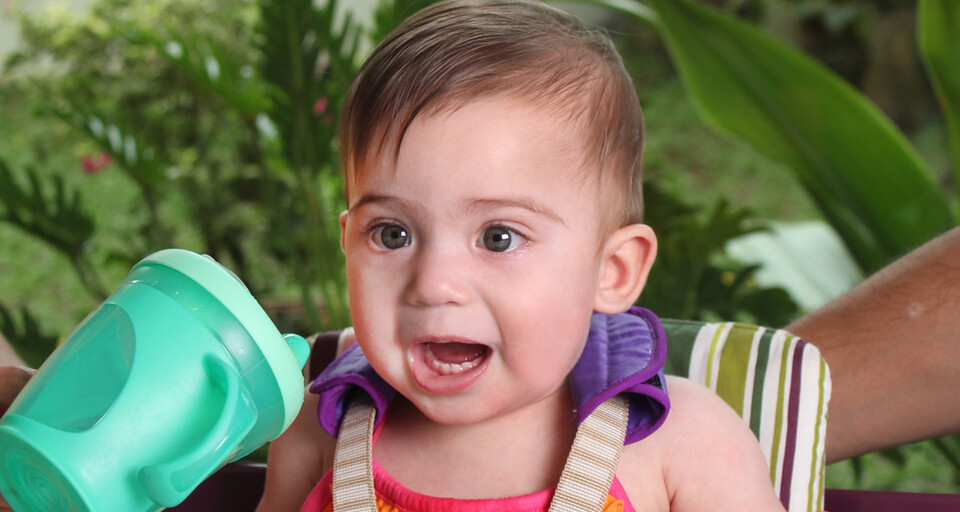 A baby drinking from baby sip cup.