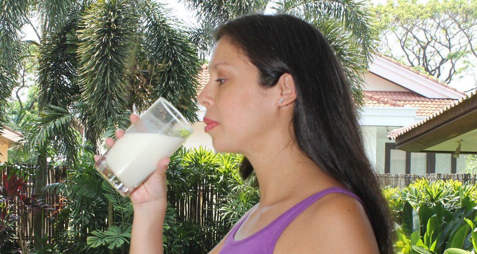 A woman is about to drink a glass of milk formulated by HiPP