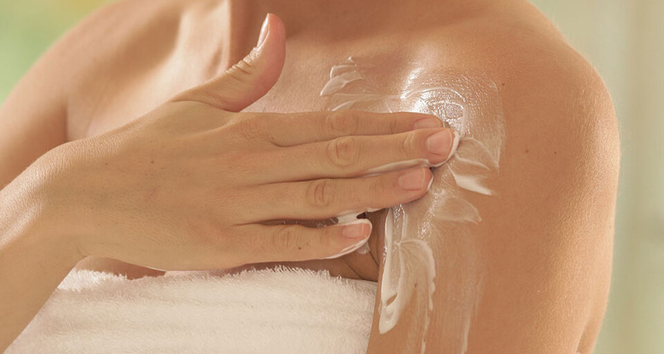 A woman applying a skincare product on her shoulder