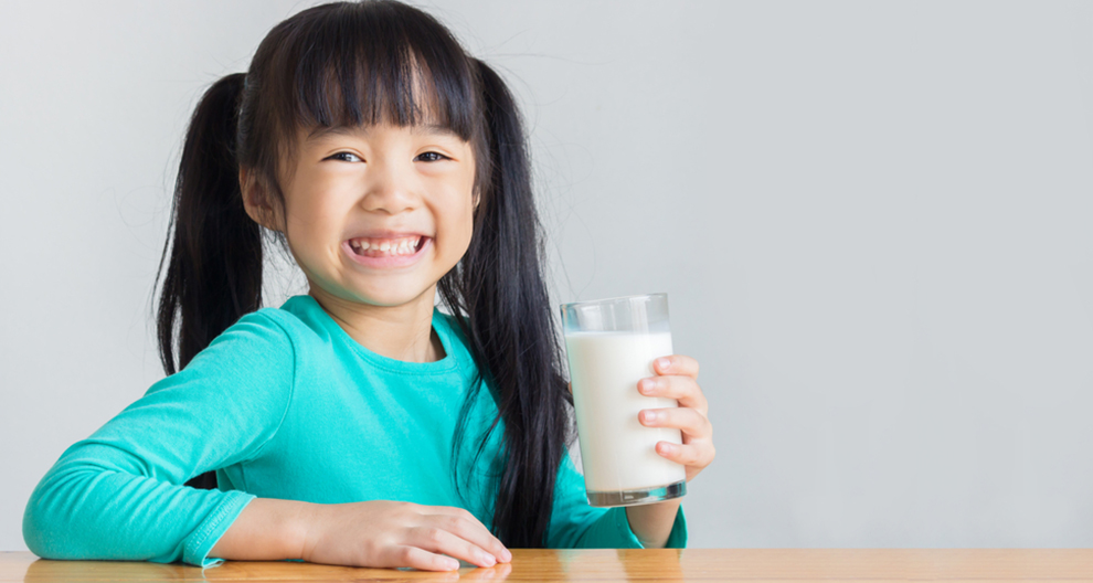 a girl smiling holding a glass of milk